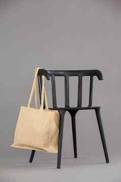 米色彩色的购物袋挂黑色的椅子