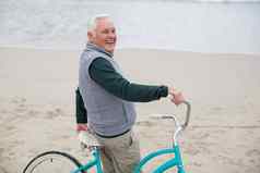 高级男人。站自行车海滩