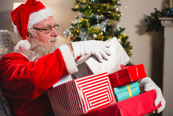 圣诞老人老人坐着堆栈礼物盒子生活房间