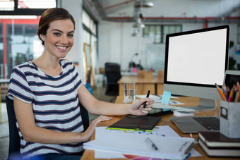 微笑女图形设计师坐着桌子上图形平板电脑桌面表格