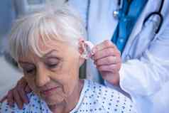 医生插入听力援助高级病人耳朵
