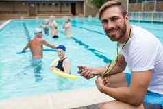 微笑游泳教练持有秒表在游泳池边