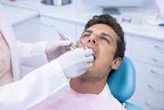 牙医持有医疗设备给治疗男人。