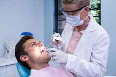 牙医持有医疗设备给治疗病人