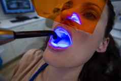 牙医检查女病人牙科固化光