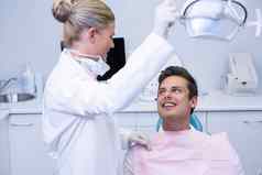 牙医调整电光病人坐着椅子诊所