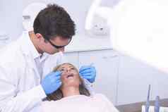 高角视图牙医持有设备检查女人