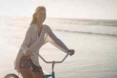 肖像微笑女人骑自行车海滩
