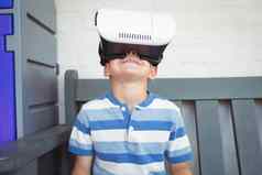 男孩看虚拟现实眼镜坐着板凳上