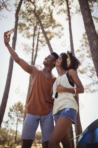 微笑年轻的夫妇点击自拍站森林