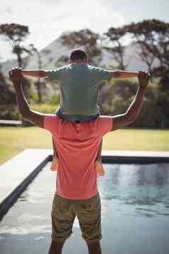 父亲携带儿子肩膀在游泳池边