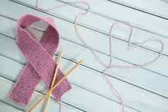 特写镜头粉红色的乳房癌症意识丝带用钩针编织针心形状