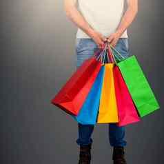 复合图像低部分男人。携带色彩斑斓的购物袋站白色背气