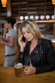 美丽的女人会说话的移动电话玻璃啤酒