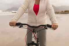 高级女人骑自行车海滩