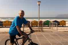 高级男人。骑自行车散步海滩