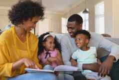 快乐非洲美国父母可爱的孩子们阅读故事书沙发