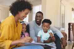 快乐非洲美国父母可爱的孩子们阅读故事书沙发