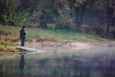 渔夫模糊海岸河湖钓鱼杆秋天清晰的一天反射水
