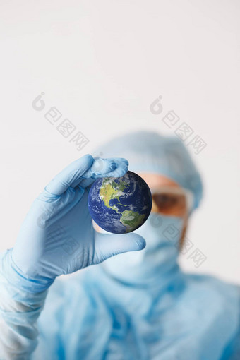 关闭医生手持有地球模拟医疗设备医生穿个人保护设备包括面具夜视镜西装保护科维德冠状病毒感染
