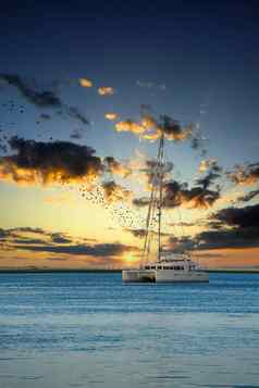 白色帆船蓝色的水日落天空