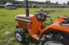 小迷你橙色拖拉机站农场院子里绿色草等待工作开始