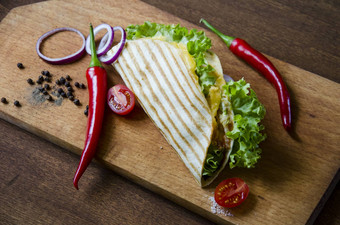 墨西哥炸玉米饼鸡肉沙拉蔬菜酱汁提出了木董事会寒冷的胡椒番茄沙拉洋葱蓝色的纸背景美味的食物新鲜的蔬菜
