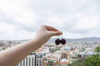 女孩手樱桃巴塞罗那背景屋顶巴塞罗那一块城市巴塞罗那显示体系结构一般空气视图夏天一天加泰罗尼亚西班牙