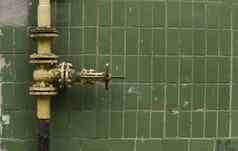 饱经风霜的气体起重机管背景绿色墙气体门黄色的颜色管块管管道起重机气体给墙