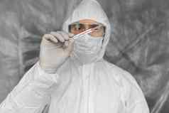 医生白色保护西装医疗面具橡胶手套持有温度计冠状病毒流感大流行疫情流感大流行冠状病毒科维德测量指示温度