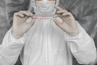 医生白色保护西装医疗面具橡胶手套持有温度计冠状病毒流感大流行疫情流感大流行冠状病毒科维德测量指示温度