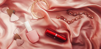 时尚时尚的配件珠宝化妆产品粉红色的丝绸背景美时尚