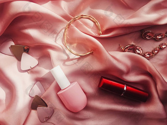 时尚时尚的配件珠宝化妆产品粉红色的丝绸背景美时尚
