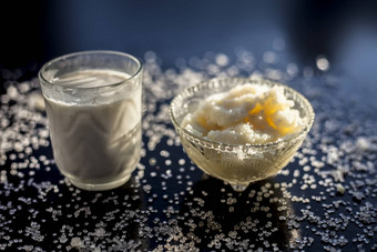 关闭玻璃碗纯牛奶混合热牛奶黑色的木光滑的表面生<strong>酥</strong>油澄清黄油糖晶体传播表面水平拍摄