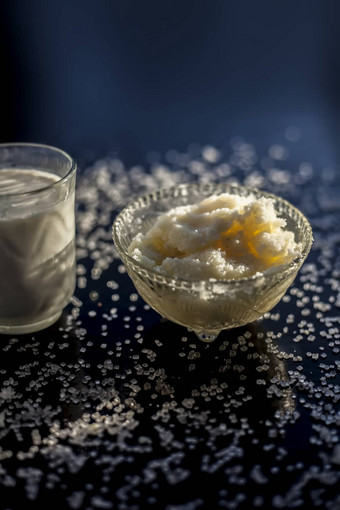 关闭玻璃碗纯牛奶混合热牛奶黑色的木光滑的表面生酥油澄清黄油糖晶体传播表面垂直拍摄