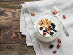 自然自制的酸奶玻璃Jar健康的食物早餐牛奶什锦早餐格兰诺拉麦片Jar酸奶油亚麻桌布木表格