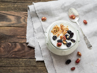 自然自制的酸奶玻璃Jar健康的食物早餐牛奶什锦早餐格兰诺拉麦片Jar酸奶油亚麻桌布木表格