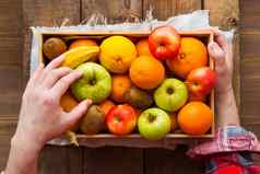 男人。格子呢格子衬衫持有盒子完整的新鲜的水果水果收获苹果橙子柠檬猕猴桃香蕉乡村木表格