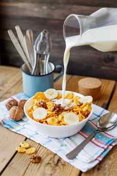 牛奶瓶流碗美味的玉米片核桃香蕉乡村木背景格子餐巾健康的脆皮早餐零食