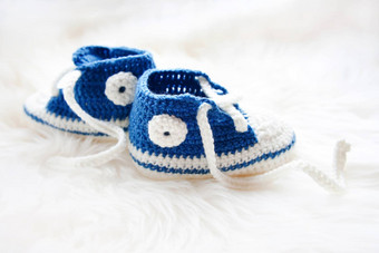 婴儿鞋子handknitted运动鞋新生儿男孩女孩用钩针编织手工制作的半靴毛茸茸的白色背景