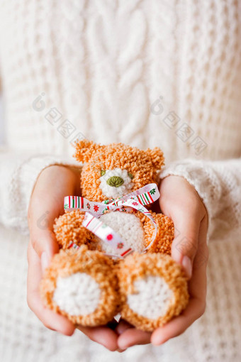 女人白色针织毛衣持有玩具熊圣诞节丝带手使钩针编织的熊现在孩子假期背景