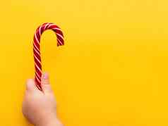 孩子持有圣诞节糖果锥黄色的背景色彩斑斓的假期甜蜜的明亮的复制空间甜点xxx红色的白色条纹