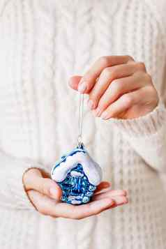 女人白色针织毛衣持有圣诞节装饰明亮的蓝色的房子闪闪发光的闪亮的象征真正的房地产假期背景