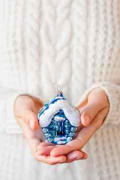 女人白色针织毛衣持有圣诞节装饰明亮的蓝色的房子闪闪发光的闪亮的象征真正的房地产假期背景