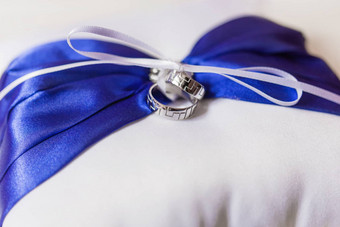 一对金婚礼环几何点缀枕头蓝色的弓丝带象征爱婚姻