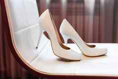 一对白色高倾斜鞋子米色椅子新娘的时尚附件婚礼