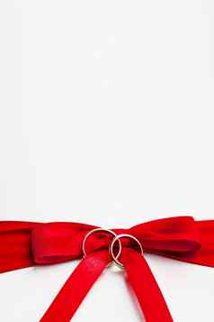 金婚礼环红色的弓白色丝绸背景婚礼细节象征爱婚姻的地方文本