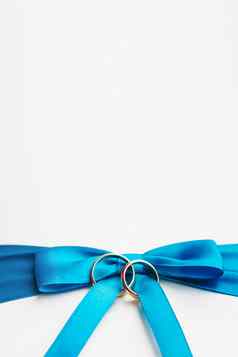 金婚礼环蓝色的弓白色丝绸背景婚礼细节象征爱婚姻的地方文本