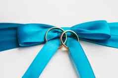 金婚礼环蓝色的弓白色丝绸背景婚礼细节象征爱婚姻