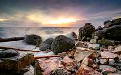 海洋水飞溅岩石海滩美丽的日落天空